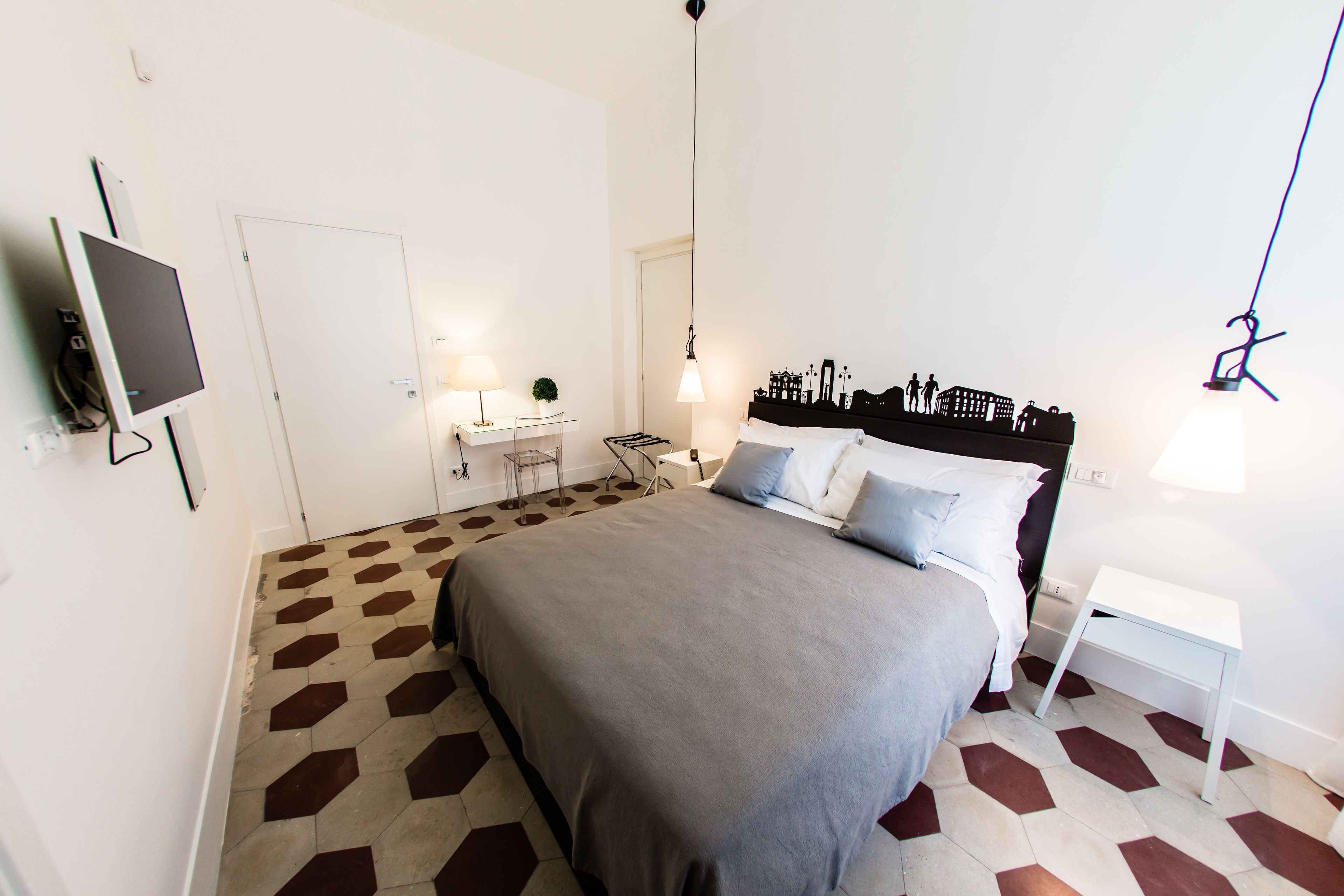 A bedroom with a bed, bedside tables, a desk, and a chair.