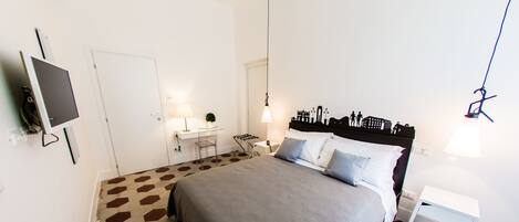 Un dormitorio con cama, mesitas de noche, escritorio y silla.