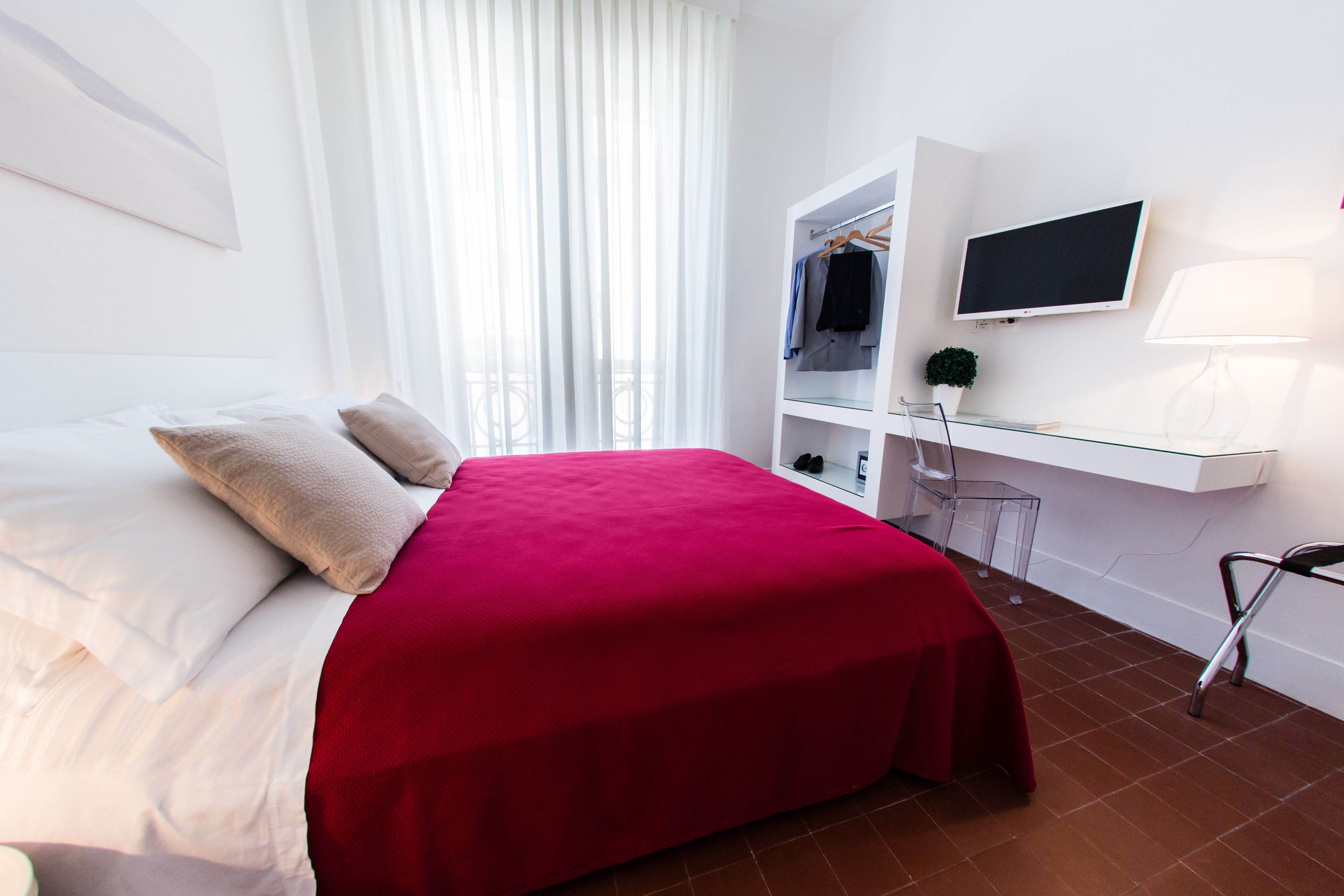 A bedroom with a bed, a wardrobe, a TV, and a lamp.