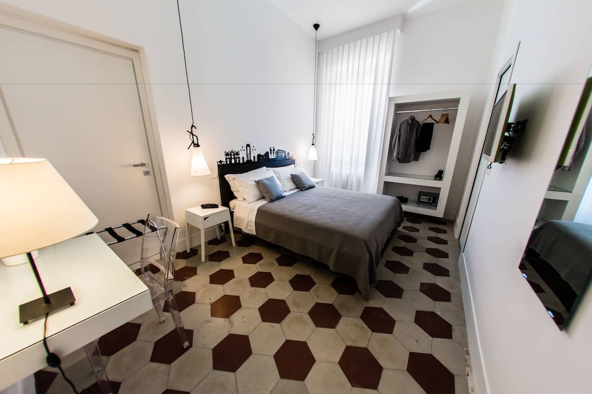 A hotel room with a bed, bedside table, lamp, and a wardrobe.