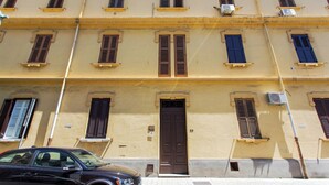 A multi-story building with a yellow facade, brown shutters, and a central door. - Rhegion B&B (Reggio Calabria)