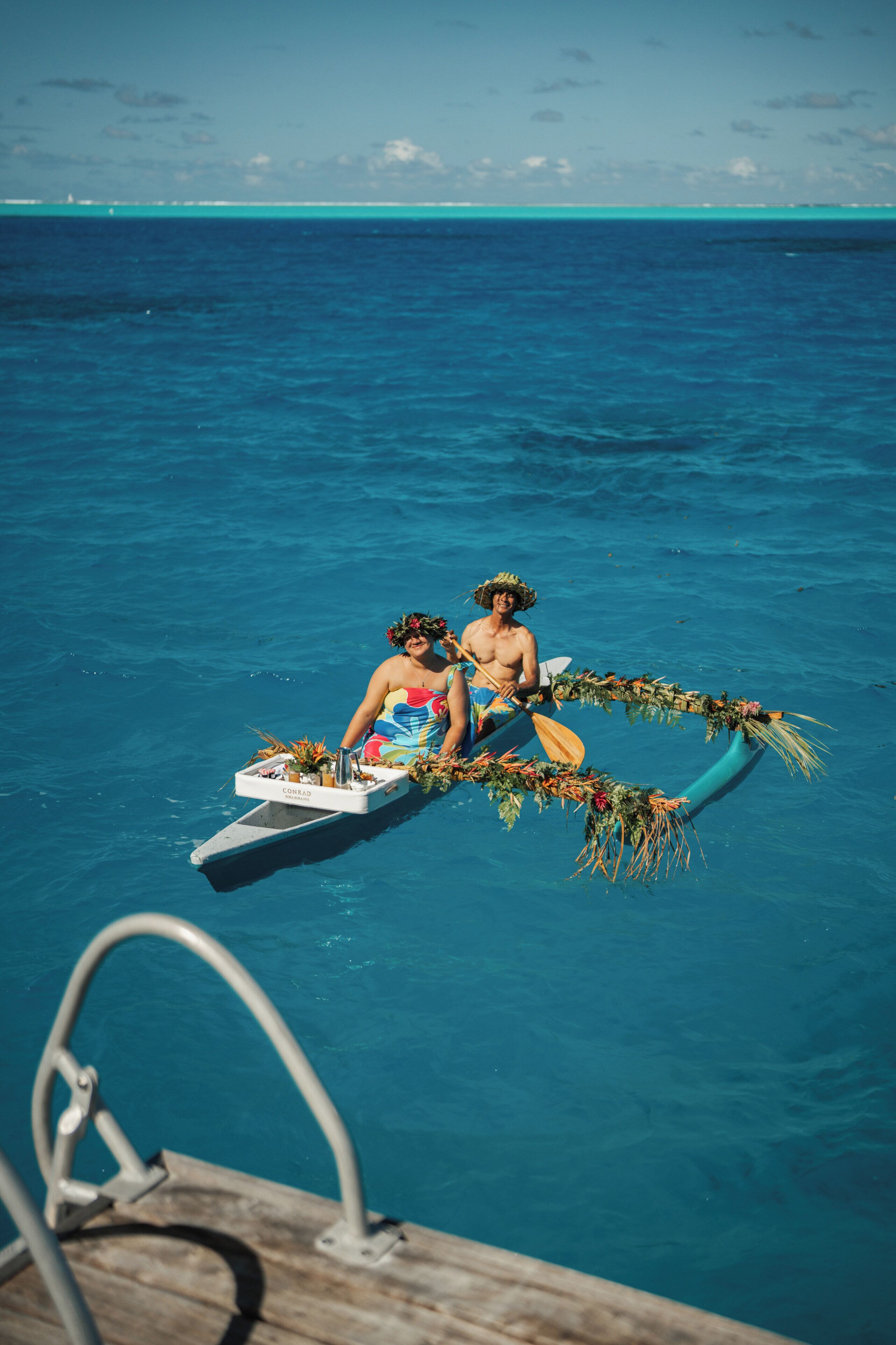 A boat with two people on a clear blue sea.