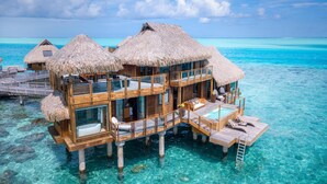 Overwater bungalows with thatched roofs, wooden balconies, and a clear blue ocean view. - Conrad Bora Bora Nui (Bora Bora)