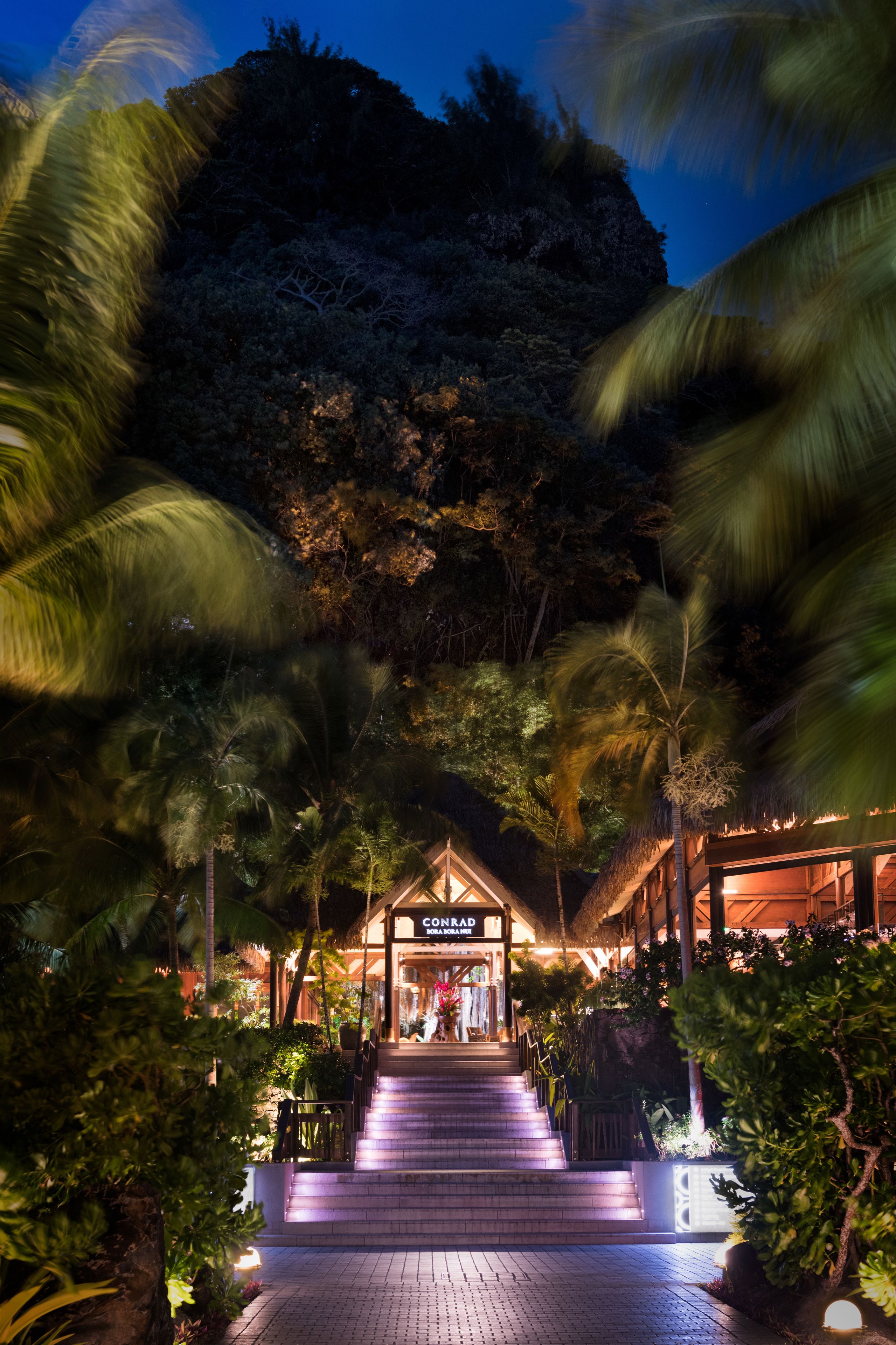 A hotel entrance with a staircase leading up to a building labeled "CONRAD".