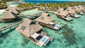 Overwater bungalows with thatched roofs, connected by walkways, and featuring infinity pools.