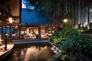 Un restaurant doté d’un toit de chaume, d’une salle à manger et d’un bassin à carpes koï.