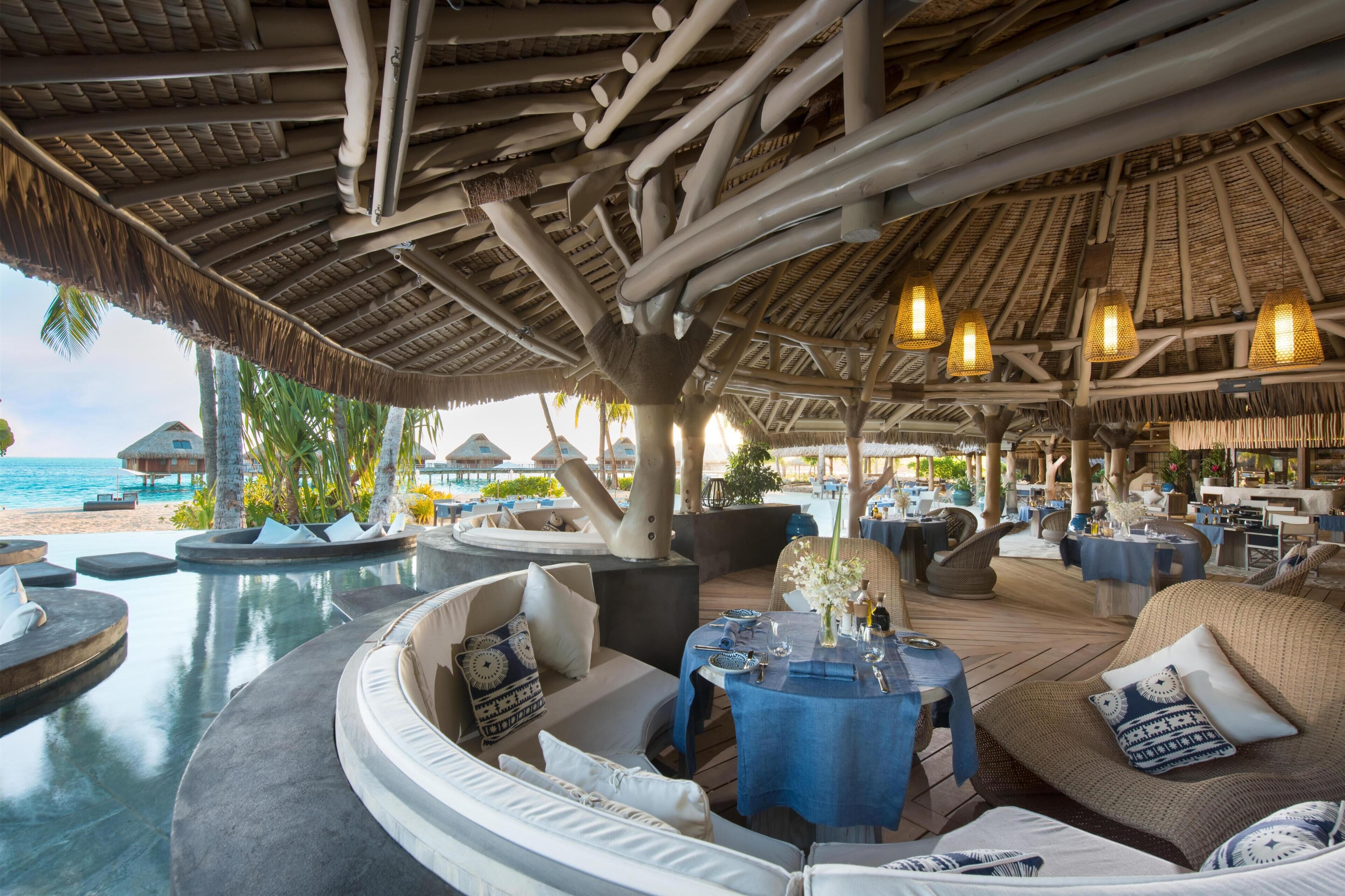 A resort with outdoor seating, a pool, and a beach view.