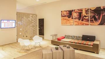 A modern living room with a sofa, chairs, a coffee table, and artwork on the wall.