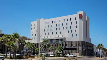 Un hotel moderno con techo plano, varios pisos y un logotipo rojo llamativo en la esquina superior derecha.