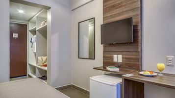 Un baño moderno con ducha, inodoro, lavamanos, espejo, televisión y un refrigerador pequeño.