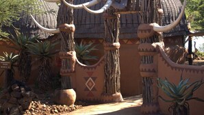 A building with a thatched roof, decorated with large tusks and rope elements. - aha Shakaland (Eshowe)