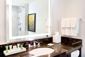 A modern bathroom with a large mirror, a round sink, and a shower. - Hilton Miami Downtown (Miami)