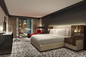 A hotel room with a bed, desk, chair, and a view of a cityscape. - Hilton Miami Downtown (Miami)