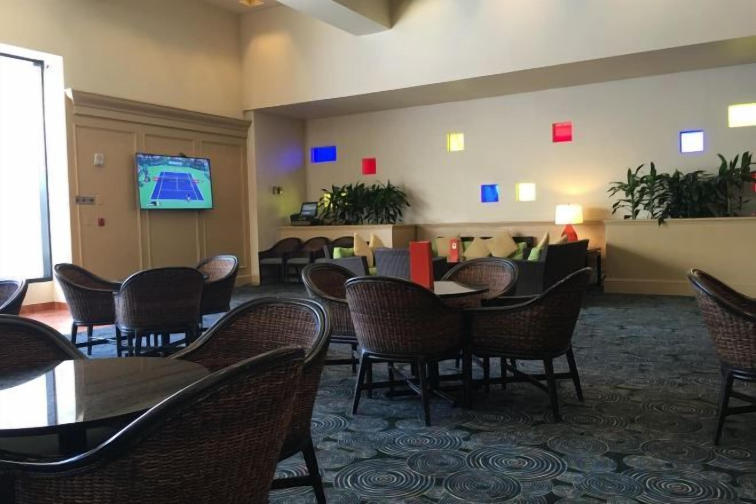 A hotel lobby with wicker furniture, a reception desk, and a television screen.
