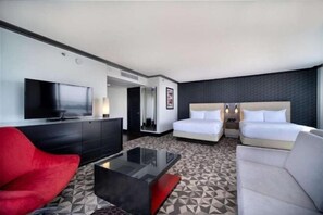A hotel room with a flat-screen TV, a red chair, a glass coffee table, two beds, and a patterned carpet. - Hilton Miami Downtown (Miami)