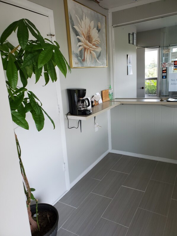 A kitchen with a coffee maker, a potted plant, and a painting on the wall. - Dollar Inn (Somerset)
