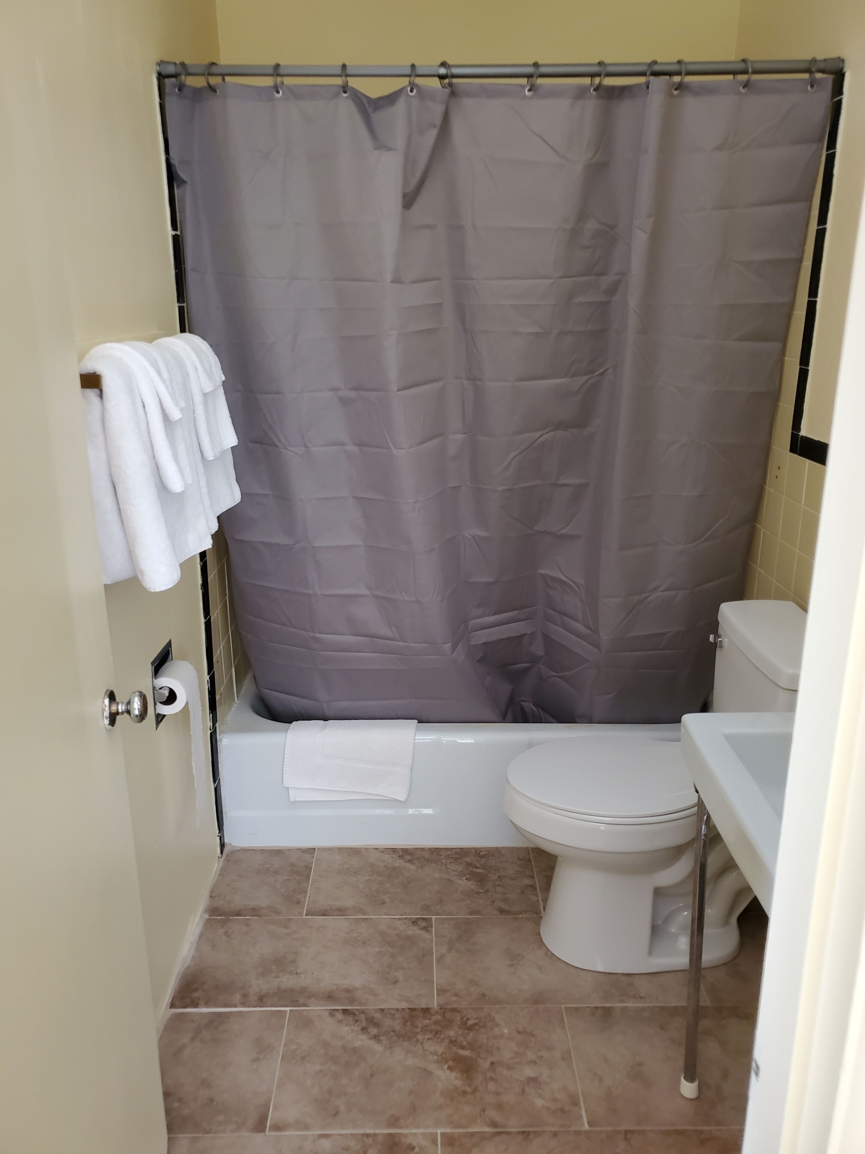 Un baño con bañera, inodoro y cortina de ducha.