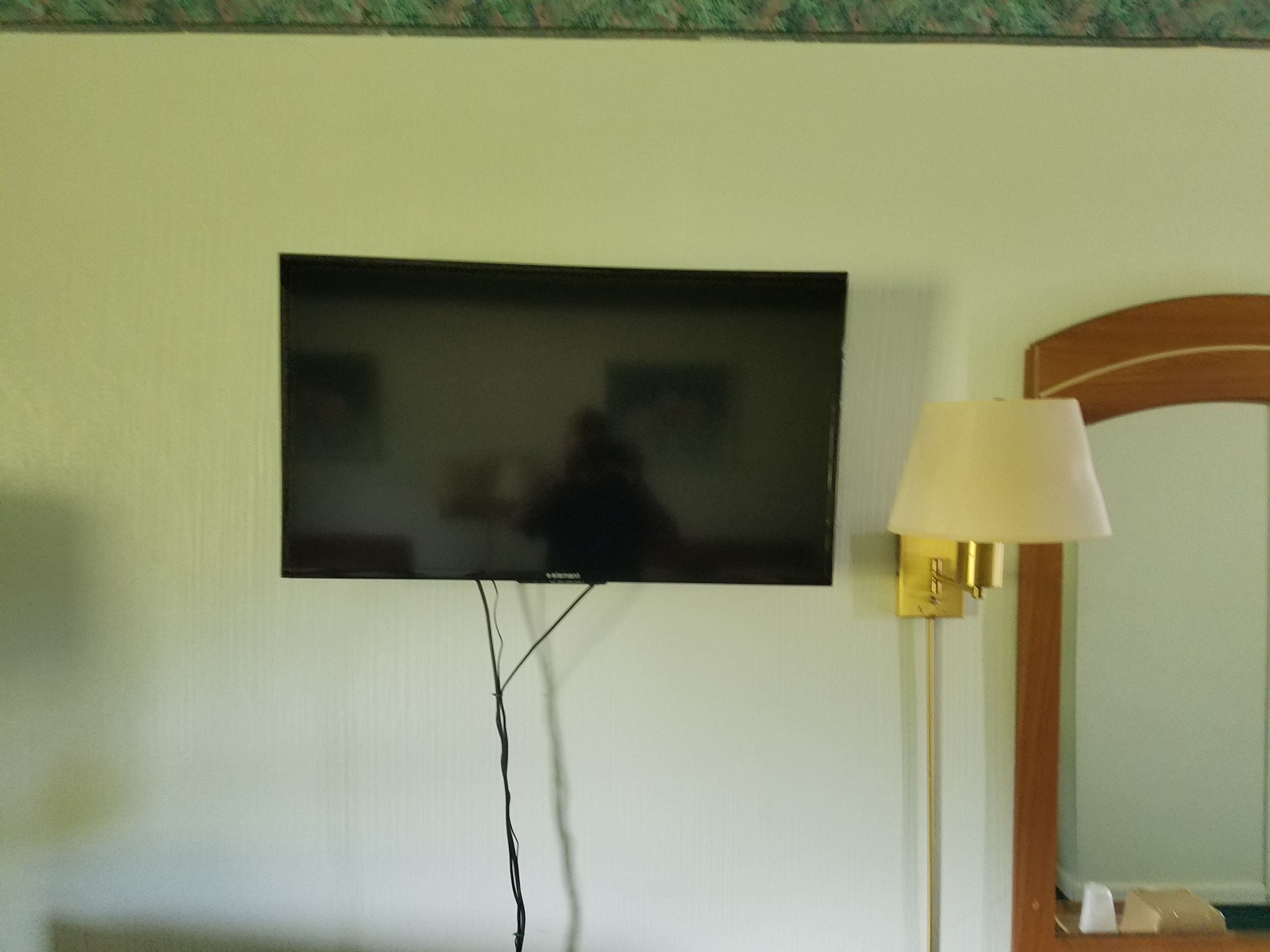 A television mounted on a wall, a lamp, and a mirror.