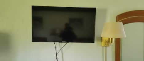 A television mounted on a wall, a lamp, and a mirror.
