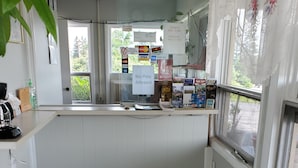 A clean, modern reception area with a check-in counter, a coffee machine, and various informational posters. - Dollar Inn (Somerset)