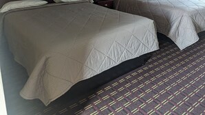 A hotel room with two beds, a nightstand with a lamp, and two framed pictures on the wall. - Dollar Inn (Somerset)