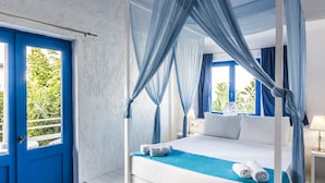 A four-poster bed with a canopy, a blue door, and a view of greenery outside. - Elmi Suites Beach Hotel - All Inclusive (Hersonissos)