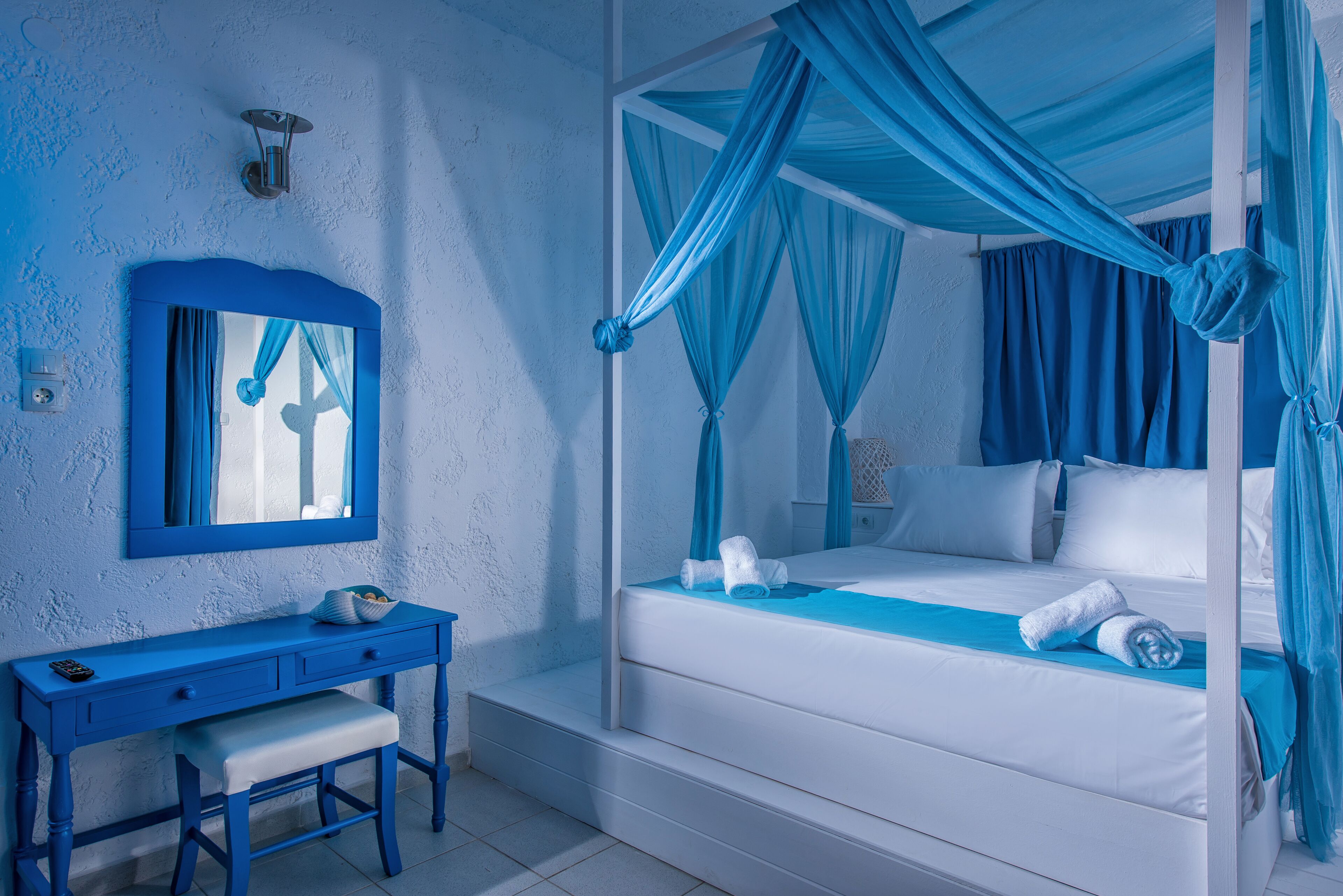 Un dormitorio con cama a dosel, una mesita de noche y un espejo.