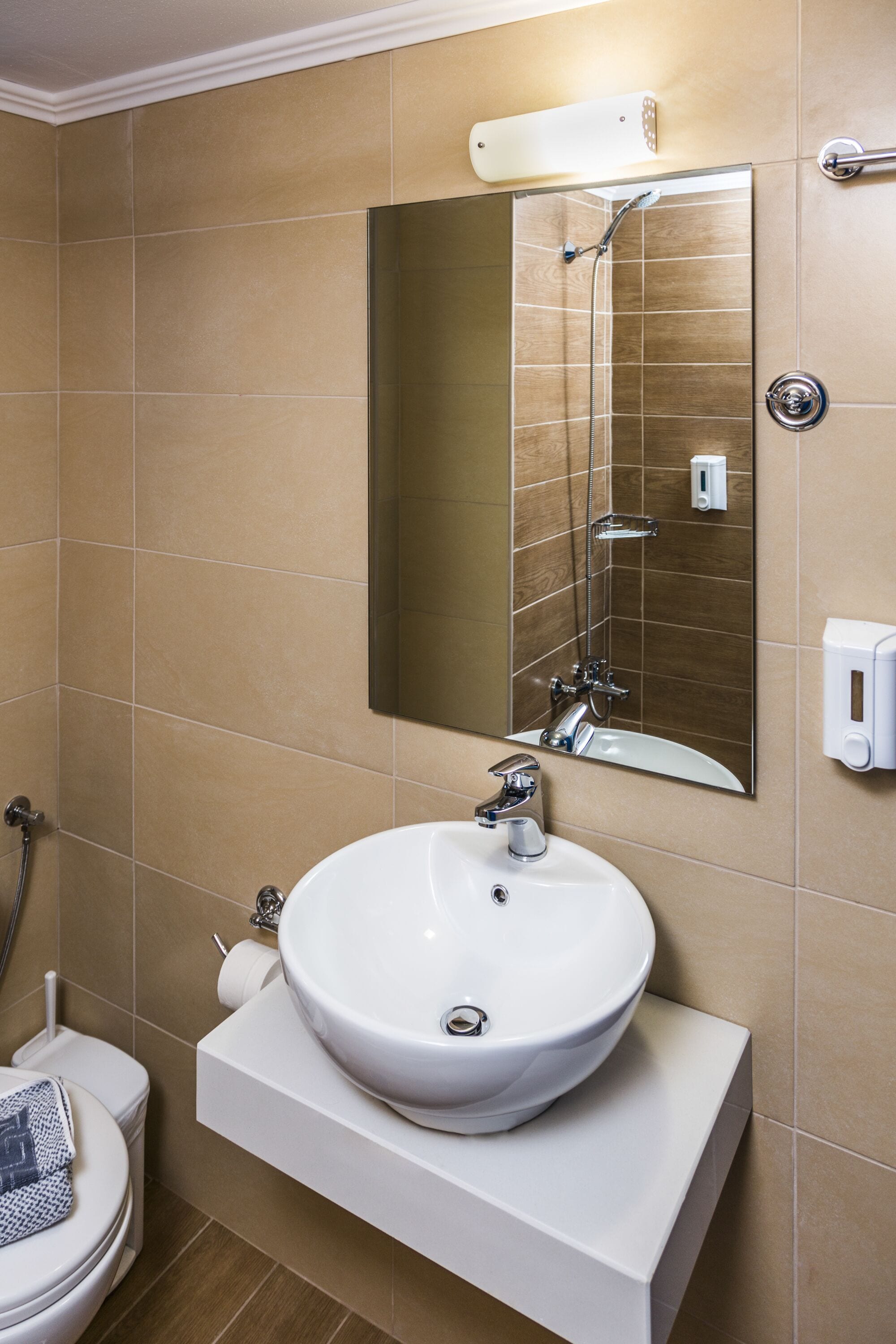 A bathroom with a white sink, mirror, and beige tiles.