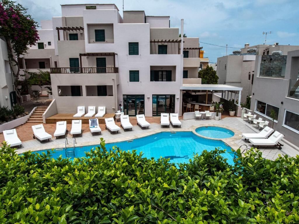 A modern building with a swimming pool surrounded by lounge chairs.