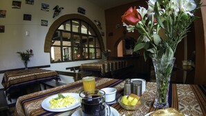 Ein Esstisch mit Frühstücksgebäck, eine Vase mit Blumen und ein Fenster mit Blick.