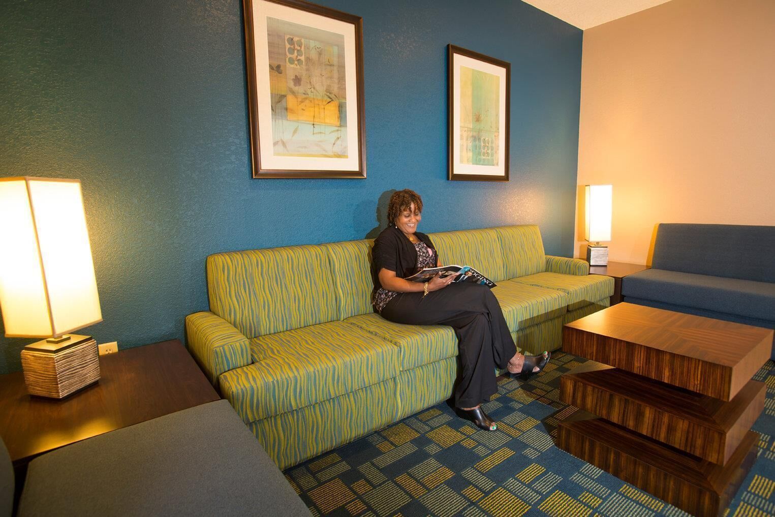 A room with a sofa, a chair, a table, and two lamps.