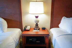 A hotel room with two beds, a bedside table with a lamp, a phone, a digital clock, and a safe. - Rosen Inn International (Orlando)