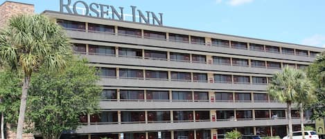 A multi-story hotel with a prominent 'ROSE INN' sign, featuring a modern architectural design with a flat roof and a series of balconies.