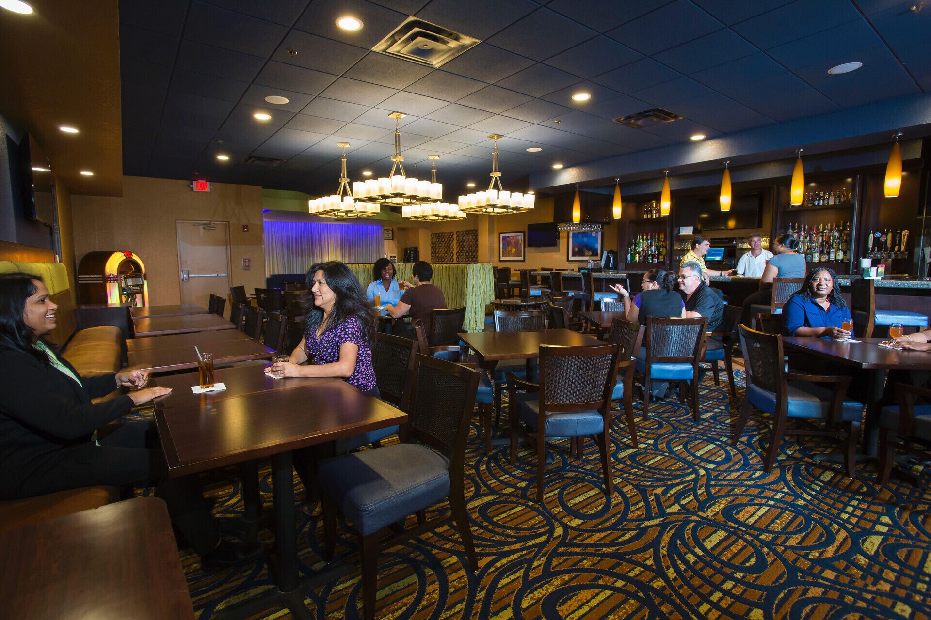 A hotel bar area with tables, chairs, and a bar counter.