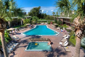 A rectangular swimming pool with a diving board, surrounded by lounge chairs and palm trees. - Rosen Inn International (Orlando)