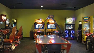 Um quarto com jogos de fliperama, mesa de bilhar e simulador de corrida.