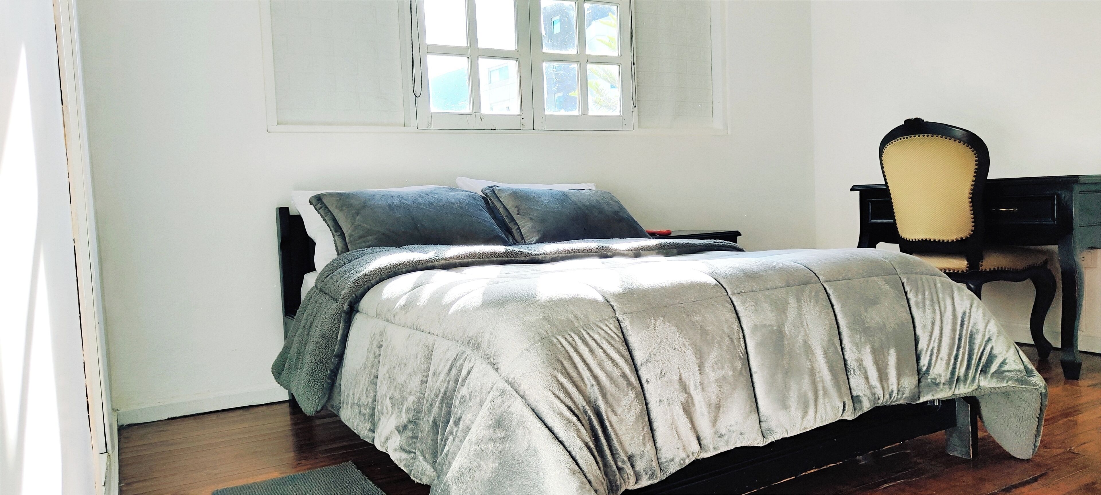 A bedroom with a bed, a desk, and a chair.