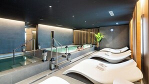 A modern spa with a pool, lounge chairs, and a wooden wall. - Neptuno Hotel & Spa (Calella)