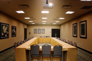 Una sala de conferències amb una taula llarga, cadires i quadres a les parets.