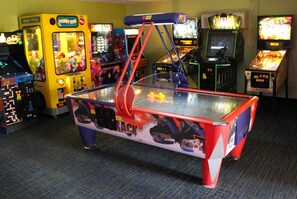 A room with a pool table, claw machines, and arcade games. - Rosen Inn at Pointe Orlando (Orlando)