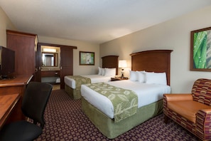 A hotel room with two beds, a desk, a television, a chair, and a bathroom.