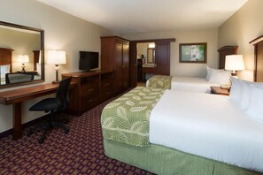A hotel room with a desk, two beds, a TV, a mirror, and a painting on the wall. - Rosen Inn at Pointe Orlando (Orlando)