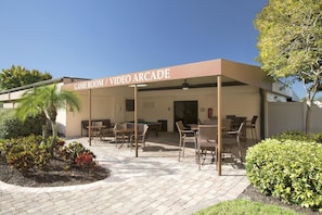A covered outdoor area with a pool table, chairs, and a sign reading 'GAME ROOM / VIDEO ARCADE'. - Rosen Inn at Pointe Orlando (Orlando)