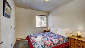 A bedroom with a bed, a nightstand, a lamp, and a window.