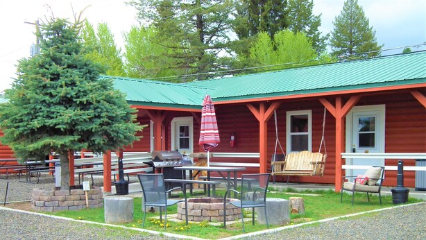A rustic cabin with a green roof, outdoor seating, and a fire pit. - Cascade Lake Inn (Cascade)