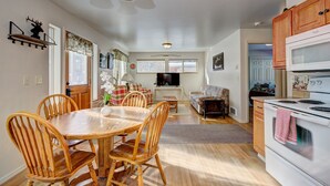 A spacious kitchen with wooden cabinets, a dining area with a wooden table and chairs, and a living room with a sofa and TV. - Cascade Lake Inn (Cascade)