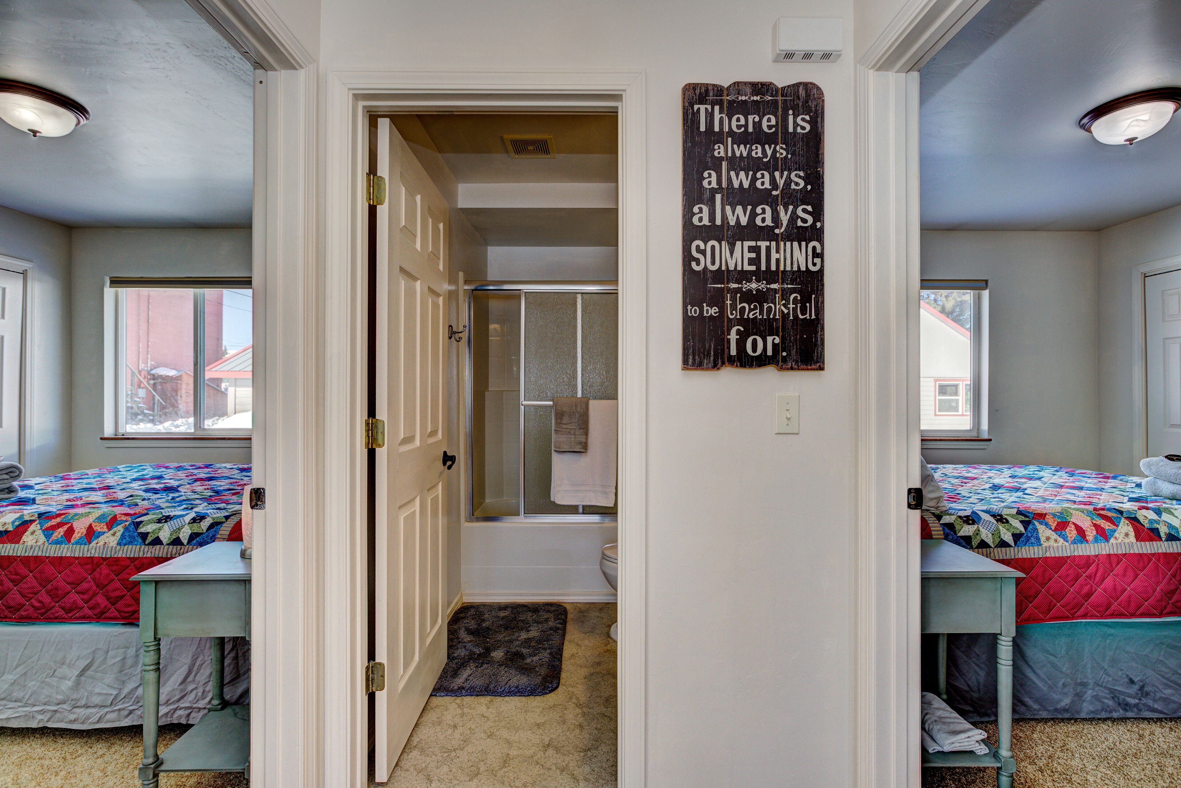 Une chambre avec deux lits, une salle de bain et un couloir.