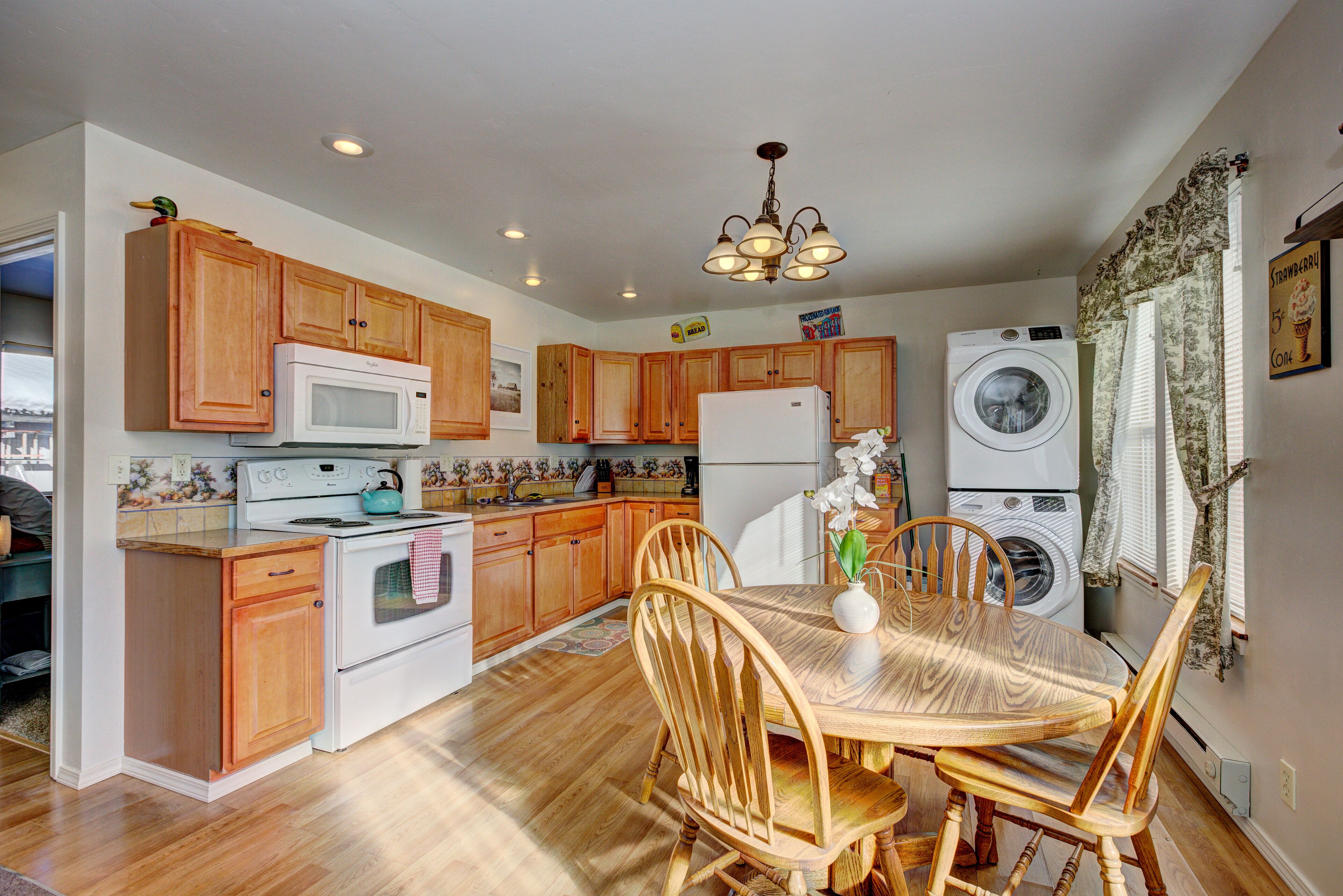 A kitchen with wooden cabinets, a microwave, stove, and a washing machine.