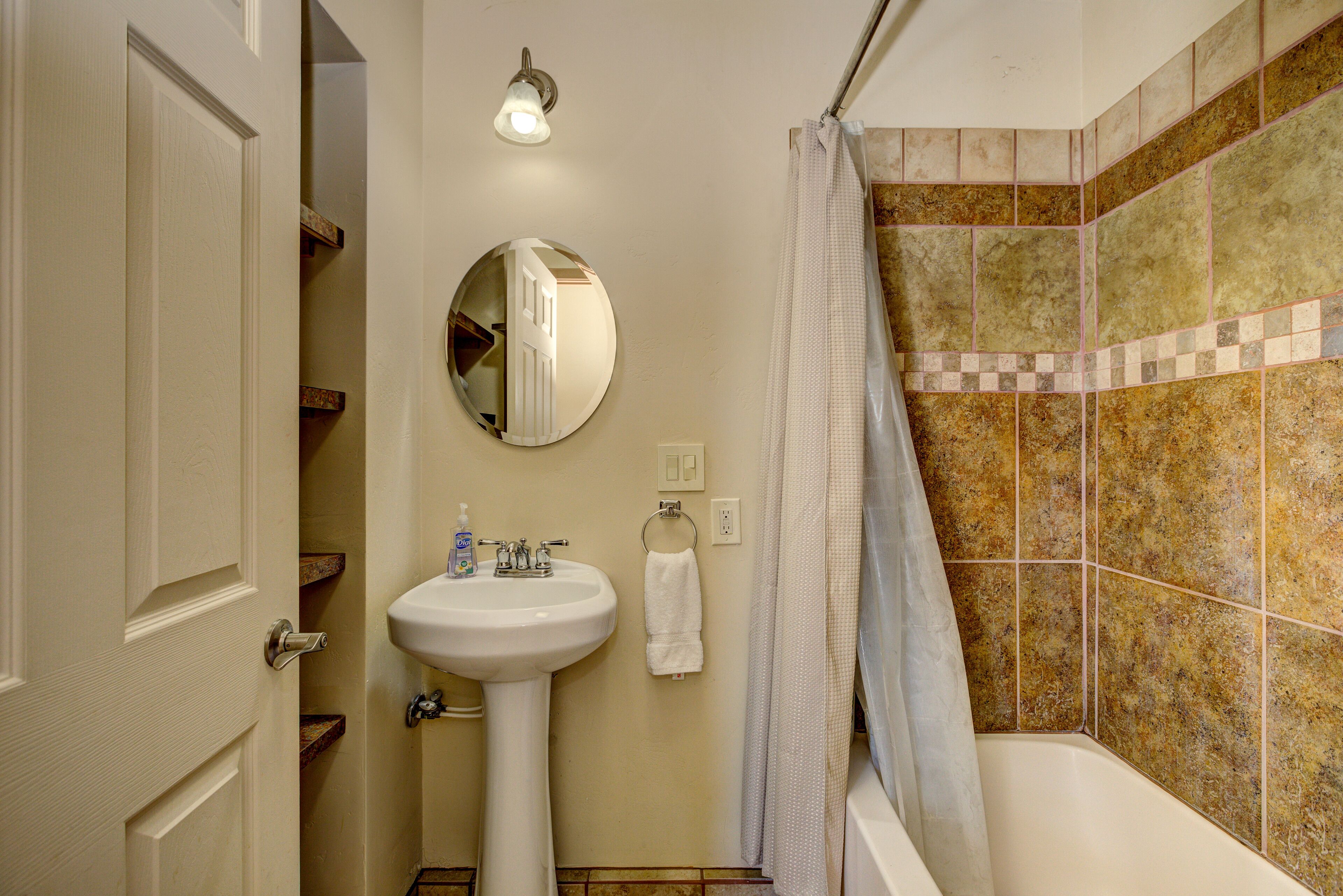 A bathroom with a white sink, mirror, and shower curtain.