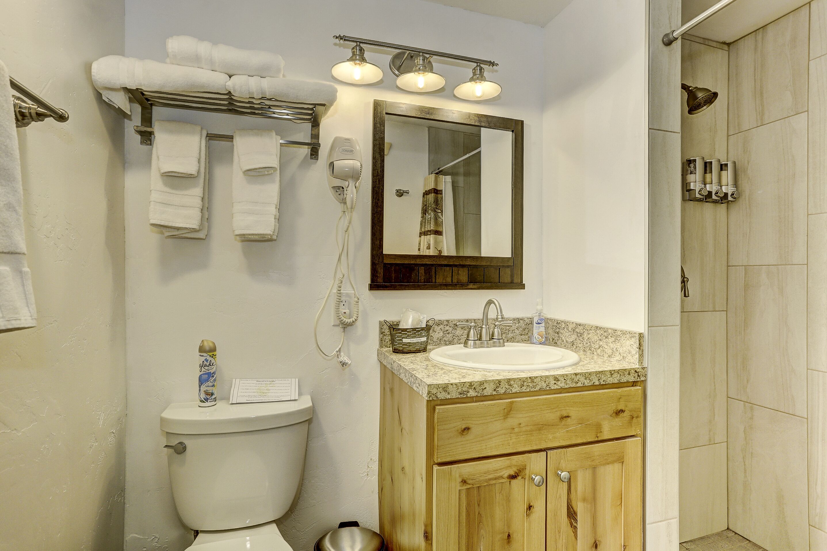 Un baño con inodoro, lavamanos, tocador y zona de ducha.